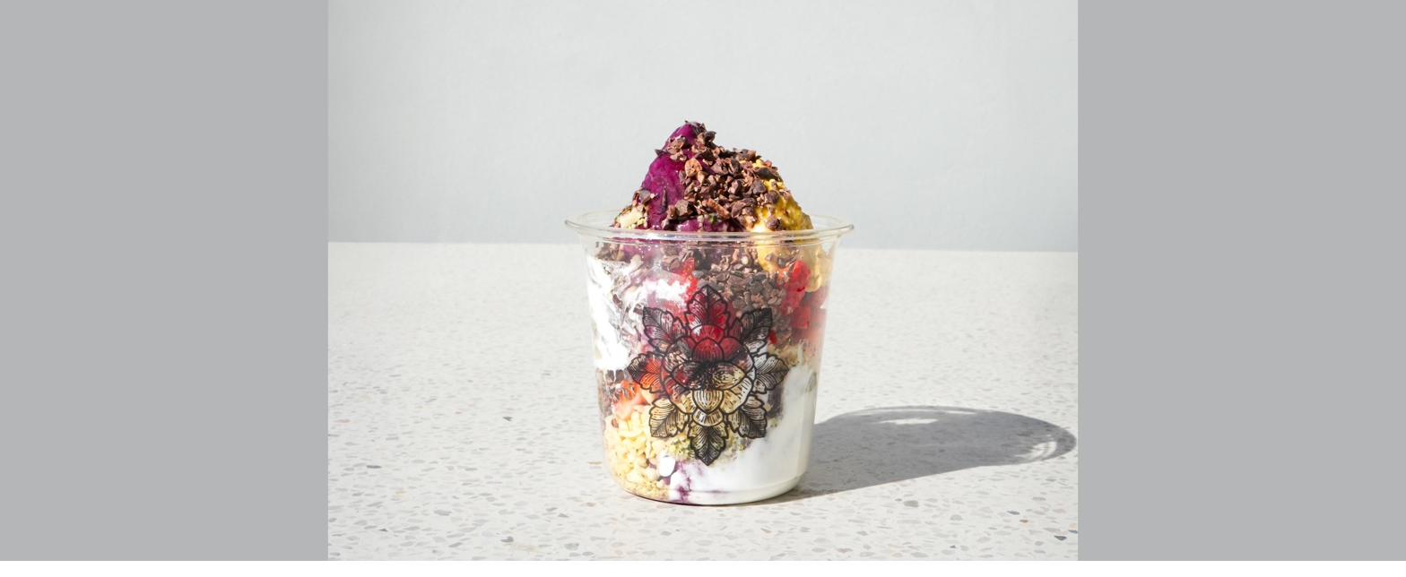 E+ROSE layered smoothie bowl with dragon fruit, berries, granola, and coconut yogurt in a lotus-print cup